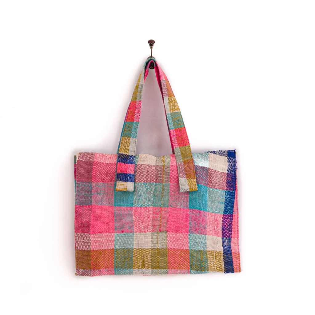Colorful checkered tote bag hanging on a single hook against a plain white background.