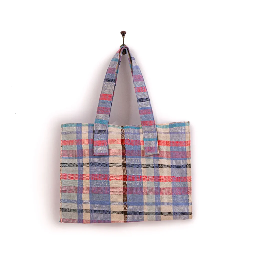 A plaid bag with blue, red, and beige stripes hangs on a wall hook.