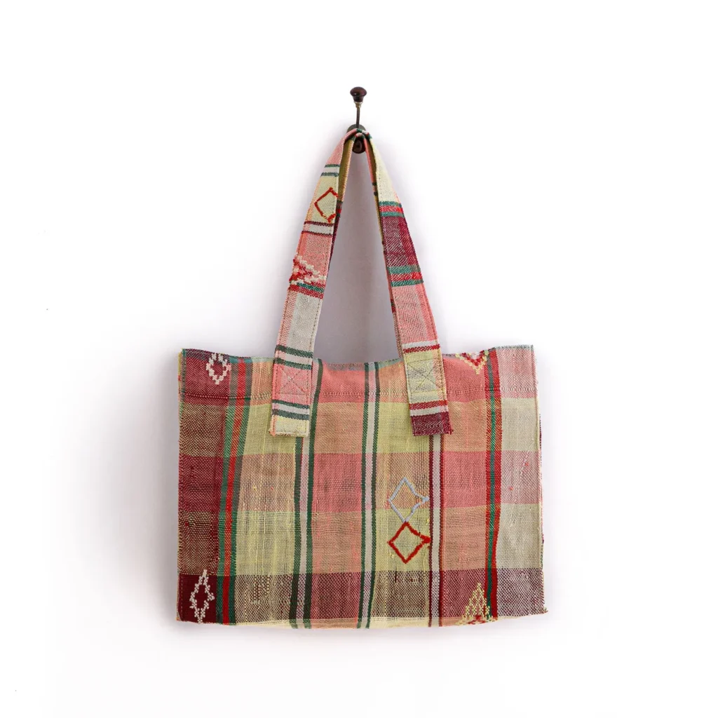 A multicolored patterned tote bag hangs on a wall hook.