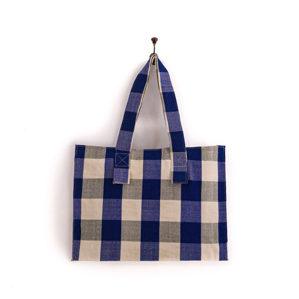 A blue and beige checkered tote bag hangs on a wall hook.