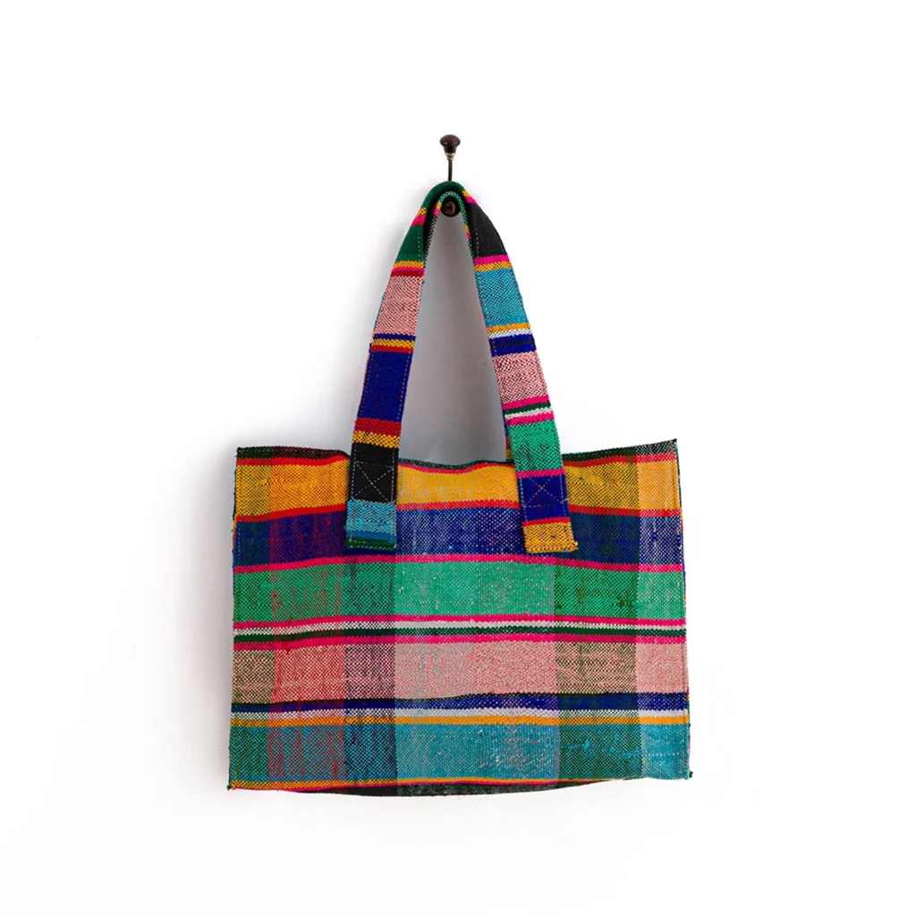 A multicolored, checkered fabric tote bag hangs on a single wall hook.