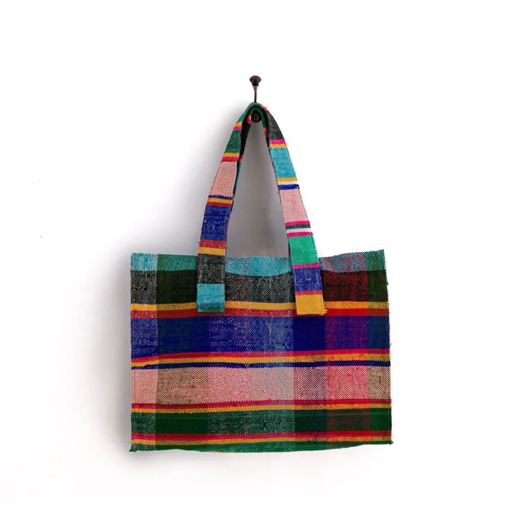 A multicolored, striped tote bag hangs on a single wall hook.