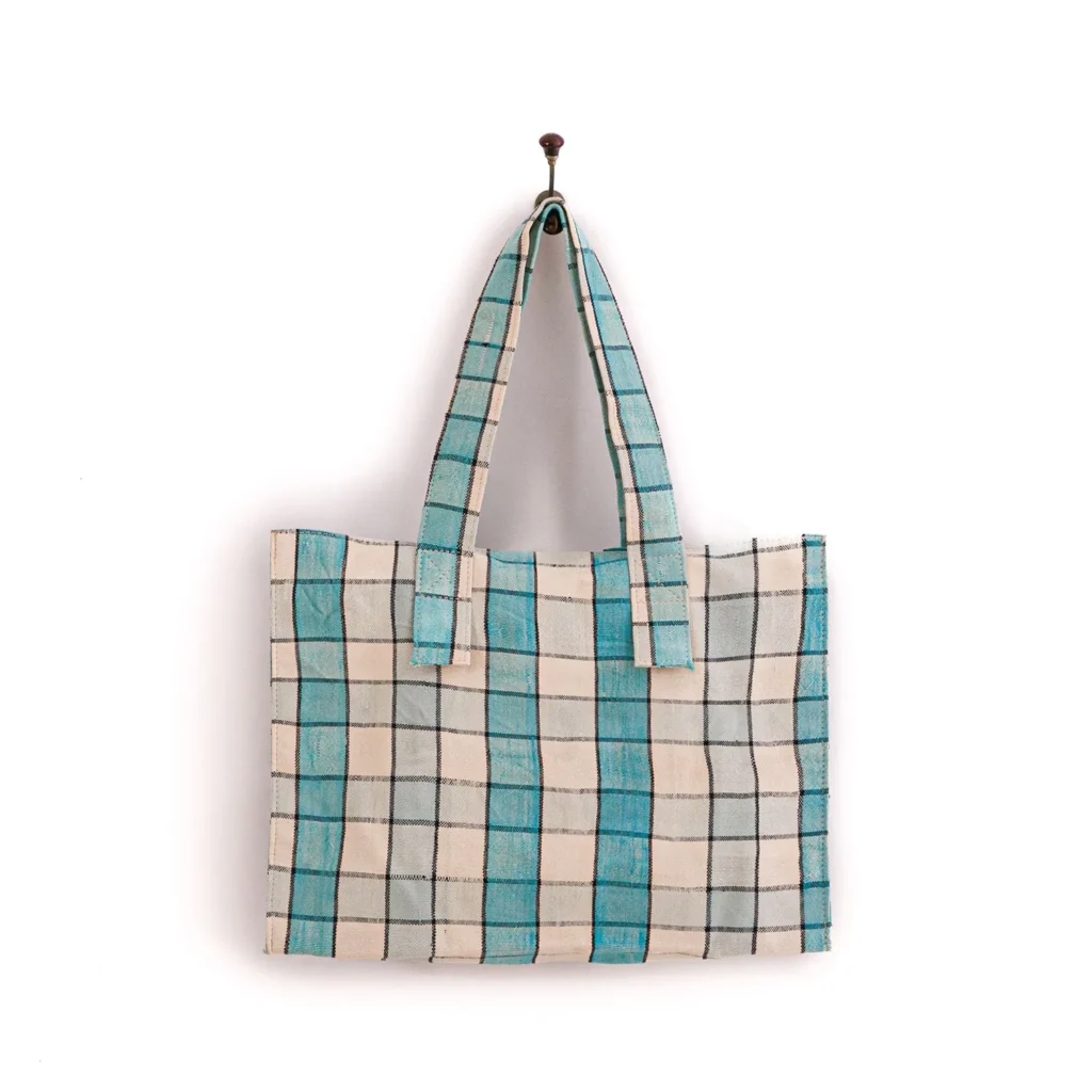 Canvas tote bag with a blue and white checkered pattern, hanging on a wall hook.