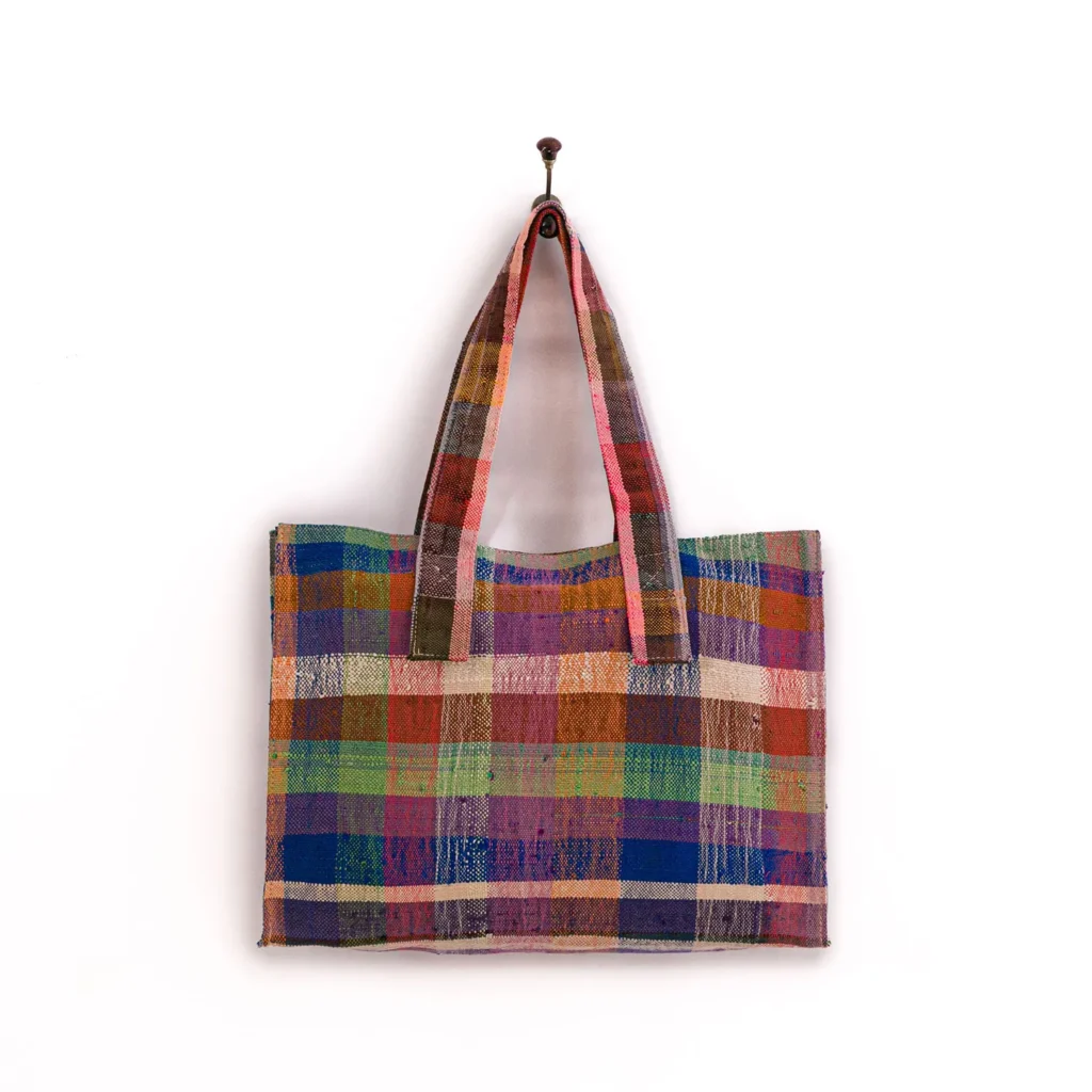 Multicolored checkered tote bag with two handles hanging on a single hook against a white background.