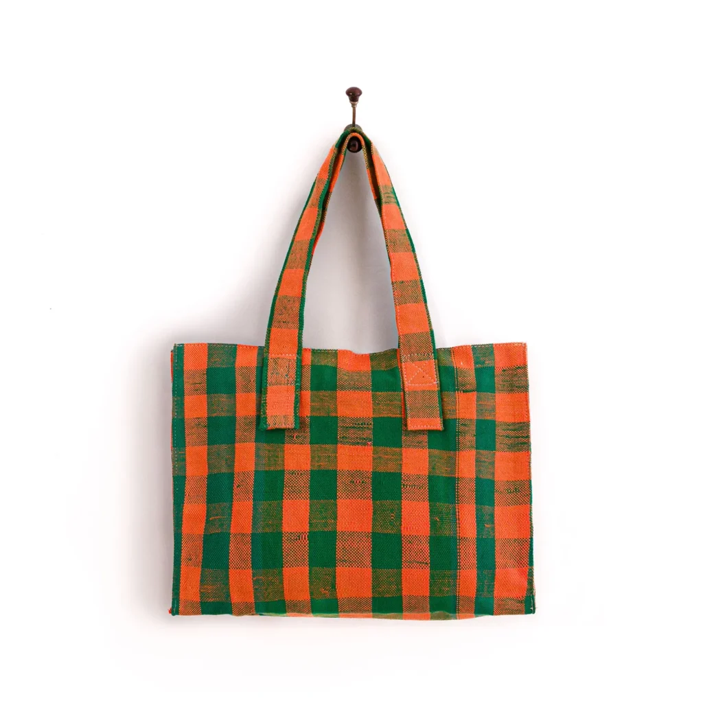 A rectangular bag with orange and green checkered pattern hangs on a hook. It has two handles.