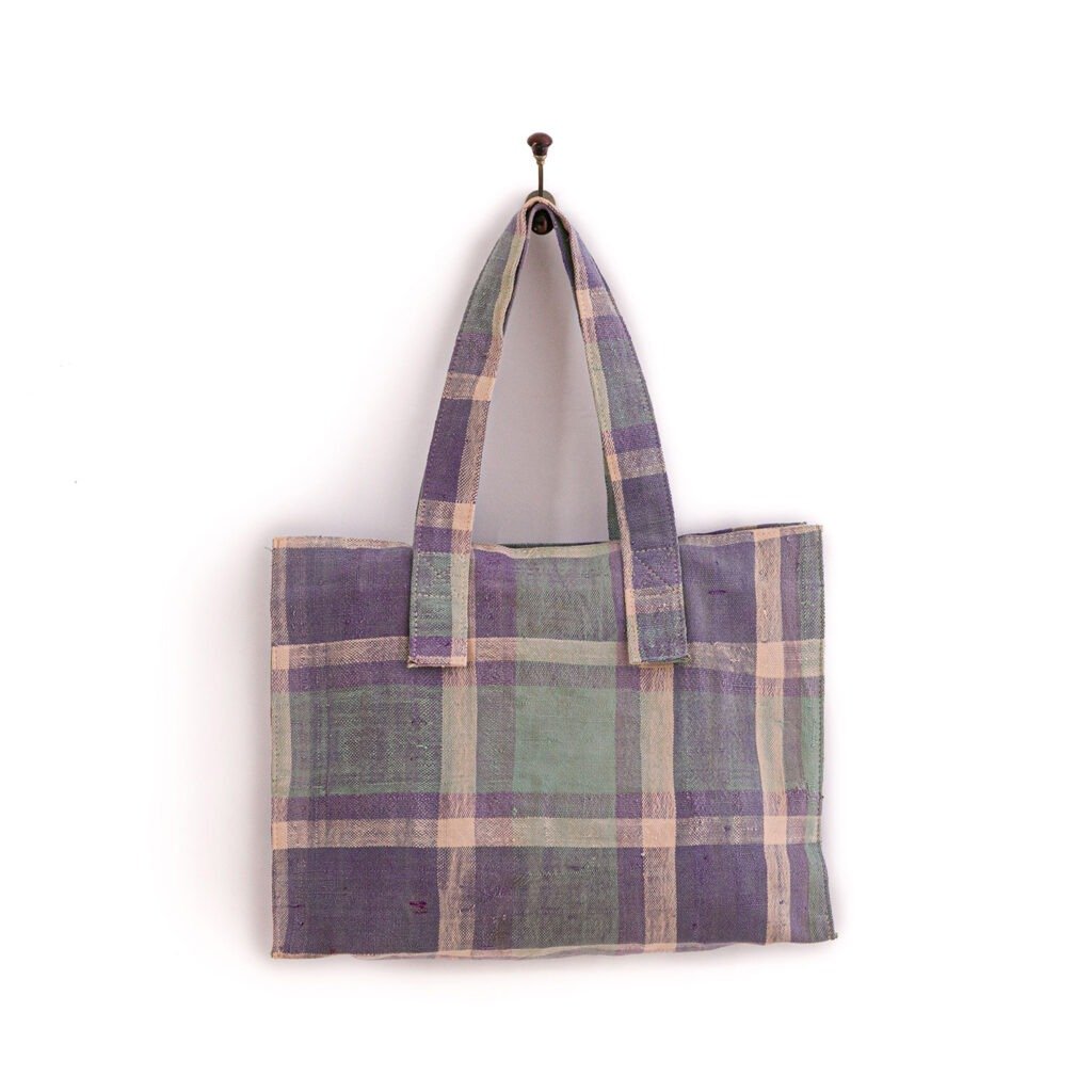 Plaid-patterned fabric tote bag hanging on a wall hook.