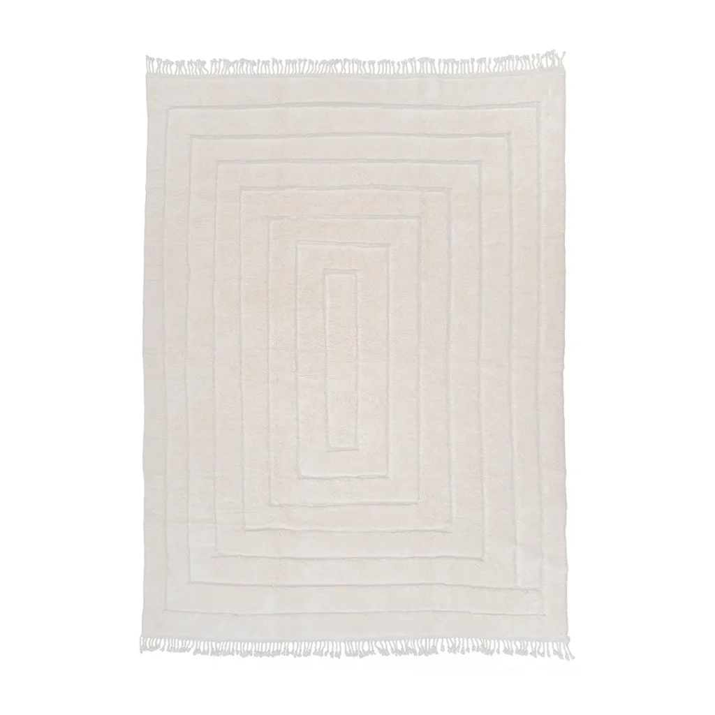 A luxurious, cream-colored rug with a raised geometric pattern and fringed edges on all sides, this hand-knotted masterpiece adds sophistication to any room.