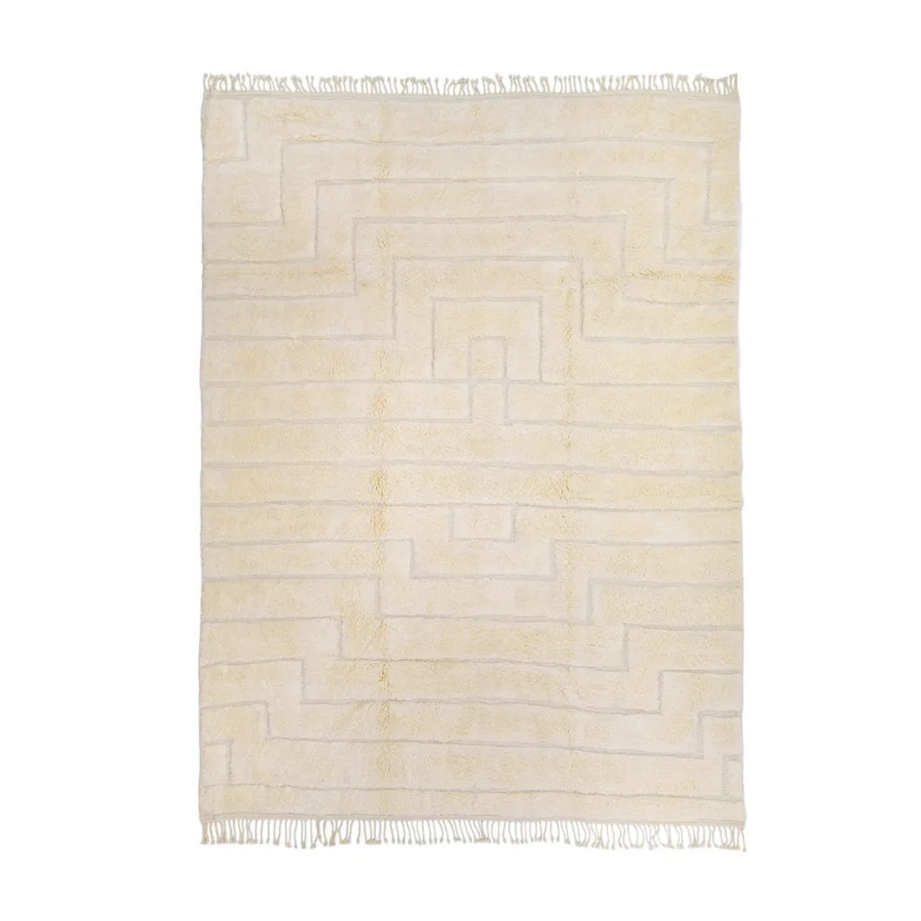 A plush beige rug featuring a geometric stepped pattern and fringed edges, perfect for adding warmth to any space.