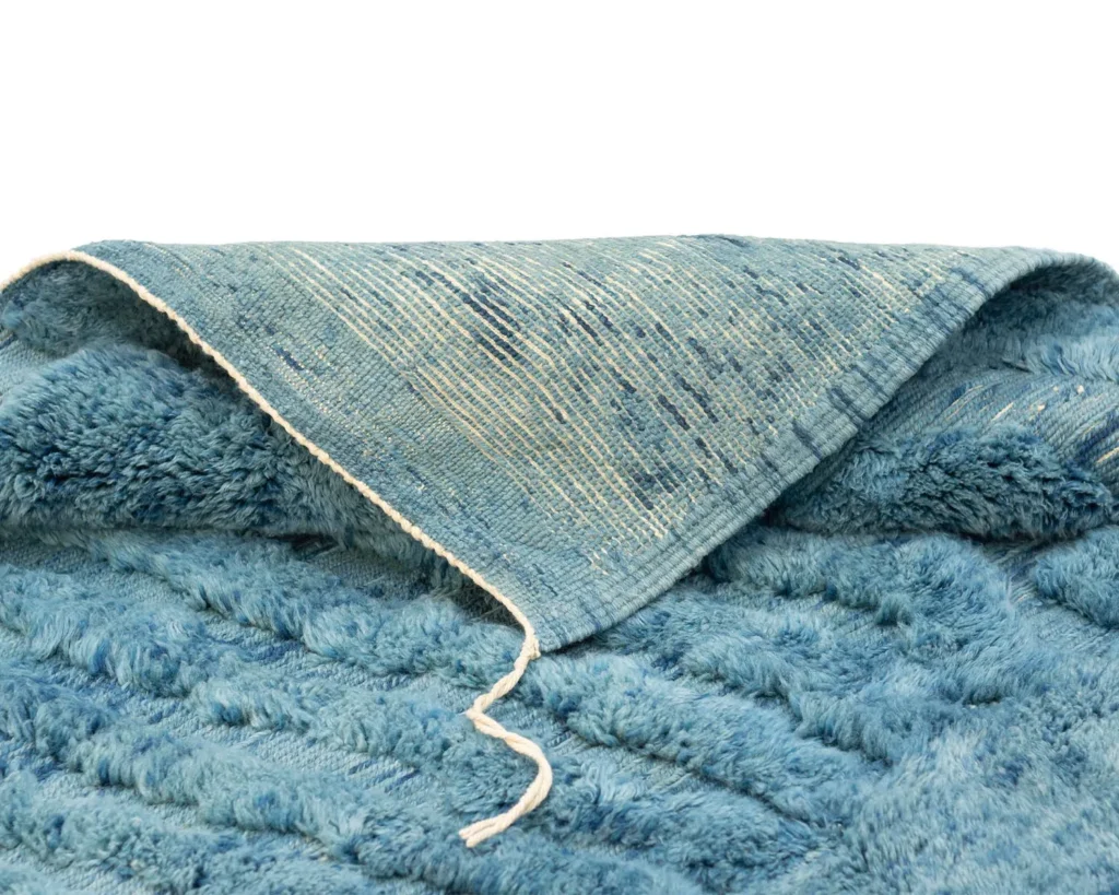 A soft, blue fleece item with a textured pattern is partially folded, revealing a contrasting woven fabric on the reverse side.