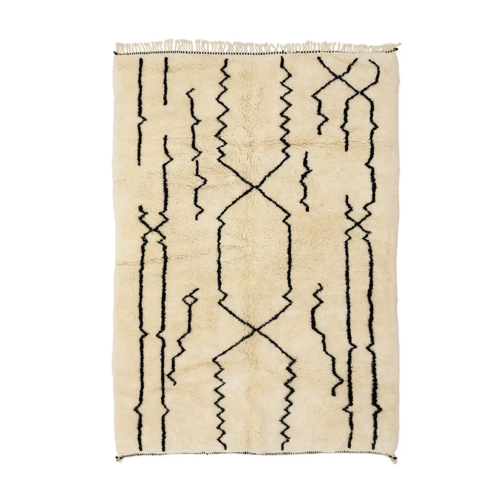 This beige, hand-knotted rug with a shaggy texture boasts abstract black zigzag and linear patterns, adding a touch of handmade home decor to any space.