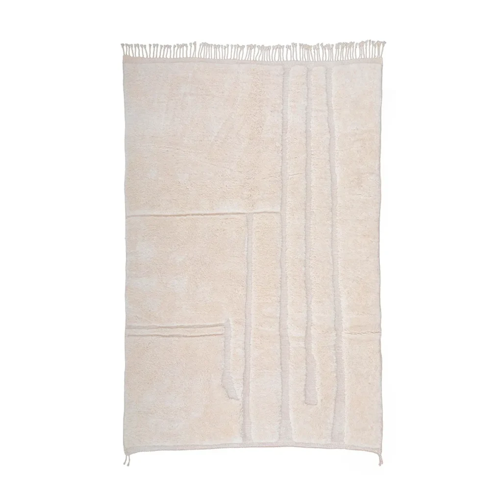 An artisanal rug in beige showcases a textured, geometric design with raised lines and fringed edges. This hand-knotted piece captures the essence of authentic Moroccan rugs, adding elegance and warmth to any space.
