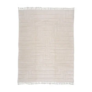 A luxurious beige rug, hand-knotted with an intricate geometric pattern and fringes on the shorter edges, adds an elegant touch to any space.