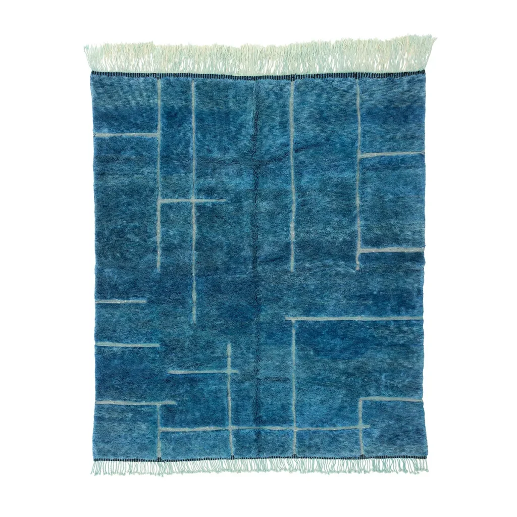 A luxurious blue rectangular rug with a geometric grid pattern features light lines and fringe at the top, showcasing a touch of Moroccan style.