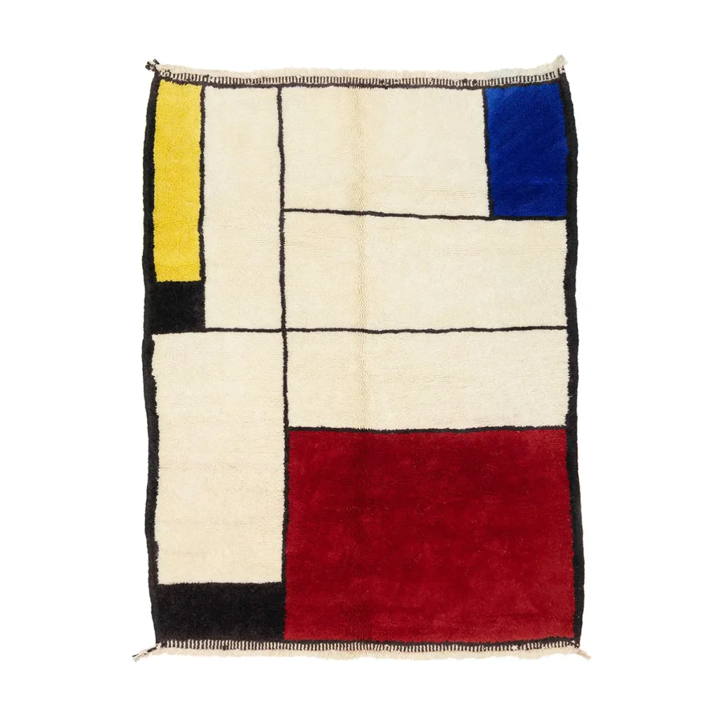 This hand-knotted luxury rug features a striking geometric pattern with large colored blocks in red, blue, yellow, black, and off-white, evoking the iconic style of Mondrians abstract art.