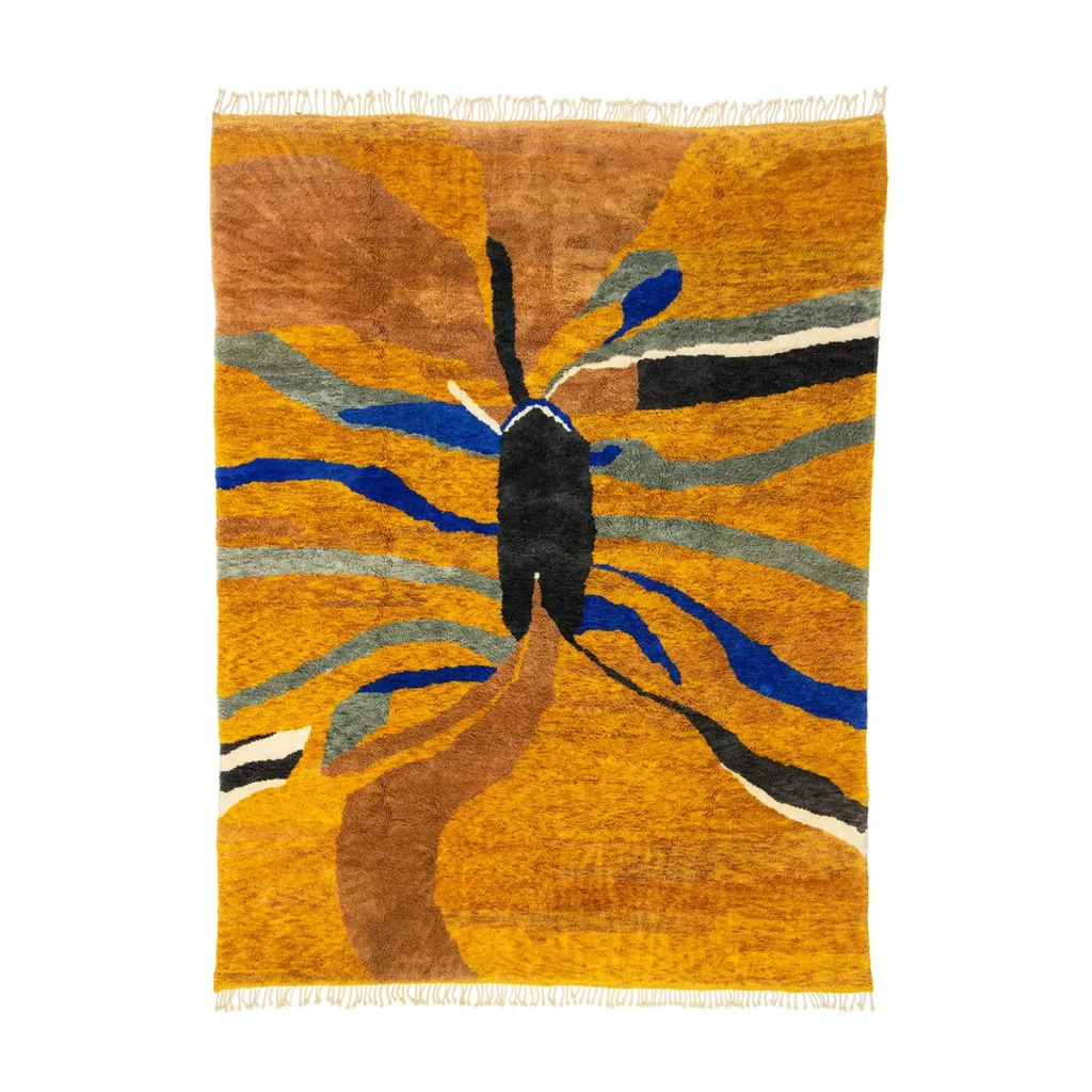 Experience the artistry of an artisanal rug with a vibrant abstract design, showcasing a central black shape with radiating blue, brown, and gray lines on an orange background. This hand-knotted masterpiece embodies the spirit of authentic Moroccan rugs, adding a unique touch to any space.