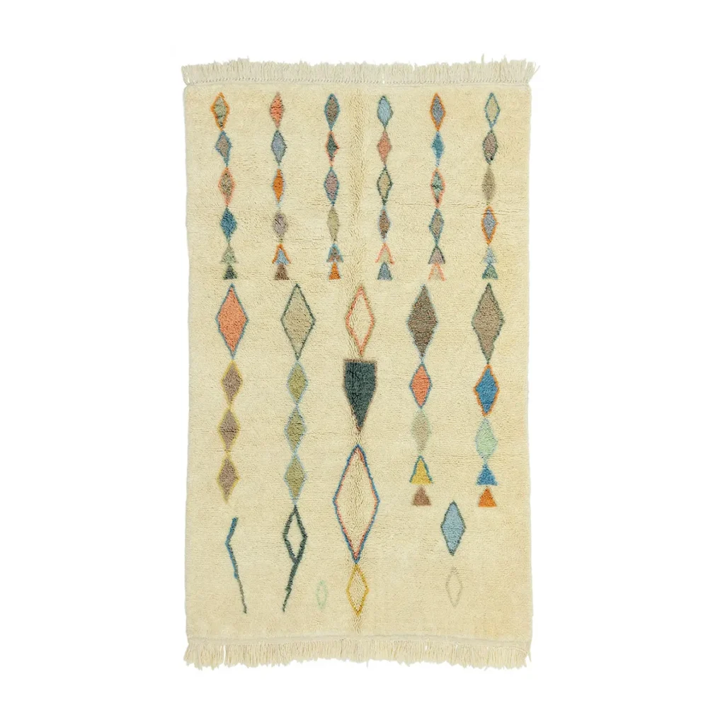 This luxury hand-knotted rug features a cream-colored design adorned with vertical rows of diamond and triangle shapes in various colors, complete with fringe on the shorter edges.
