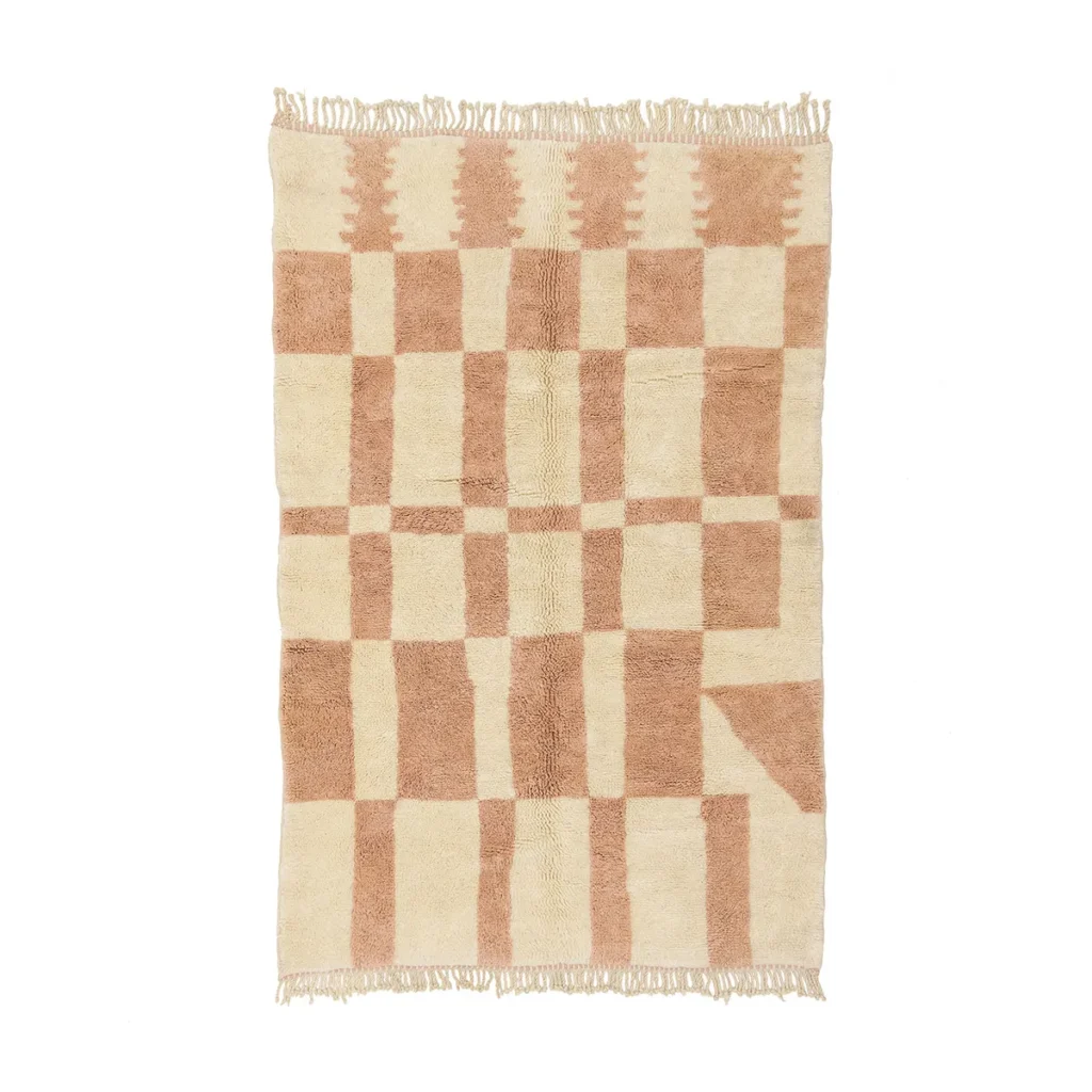 This artisanal rug, authentically inspired by Moroccan design, showcases a rectangular beige surface adorned with a light brown geometric pattern of squares and stylized tree shapes. The hand-knotted piece is elegantly finished with fringed edges on the shorter sides.