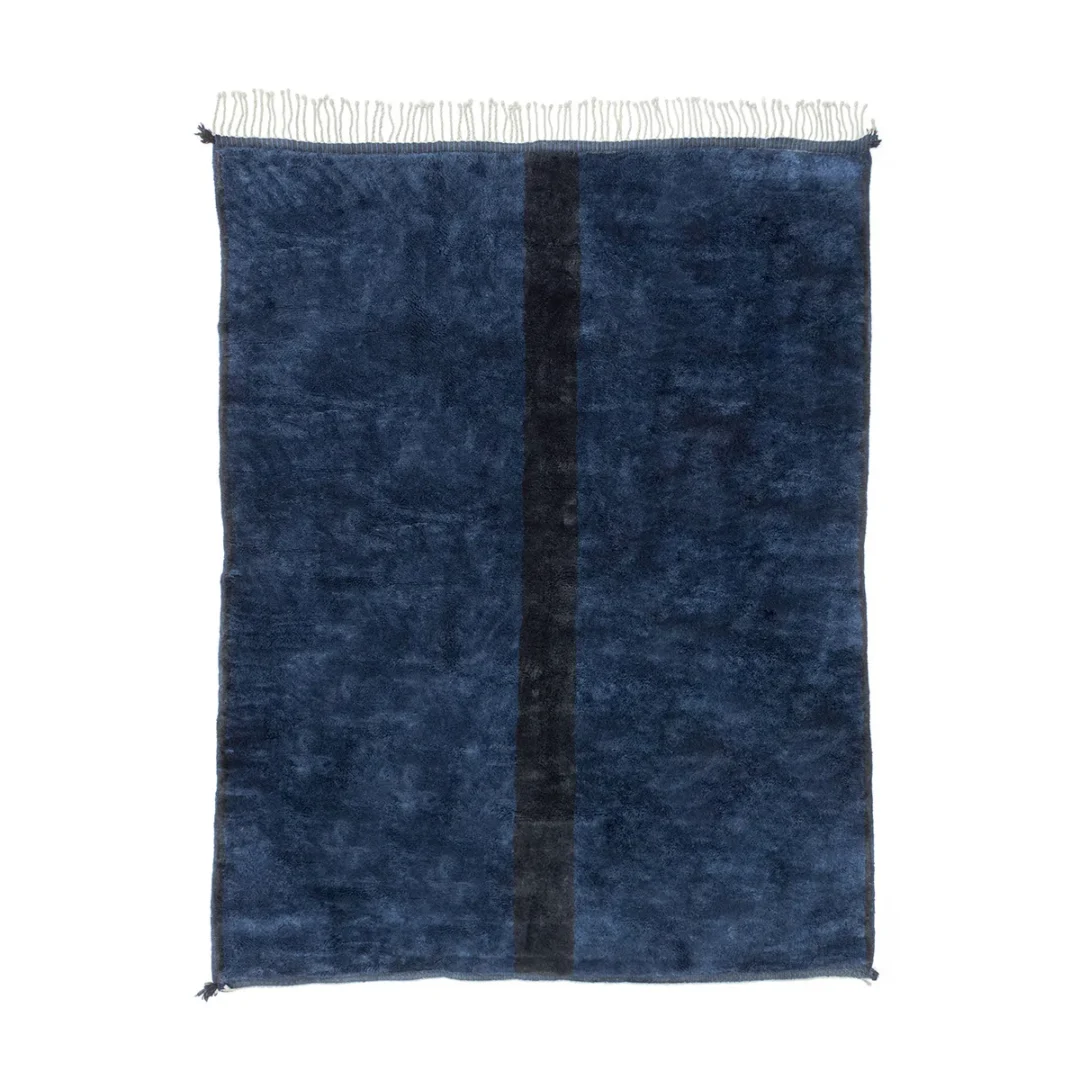 This luxurious, handmade home decor piece is a rectangular dark blue rug, featuring a vertical black stripe in the center and delicate white fringes on the top and bottom edges.