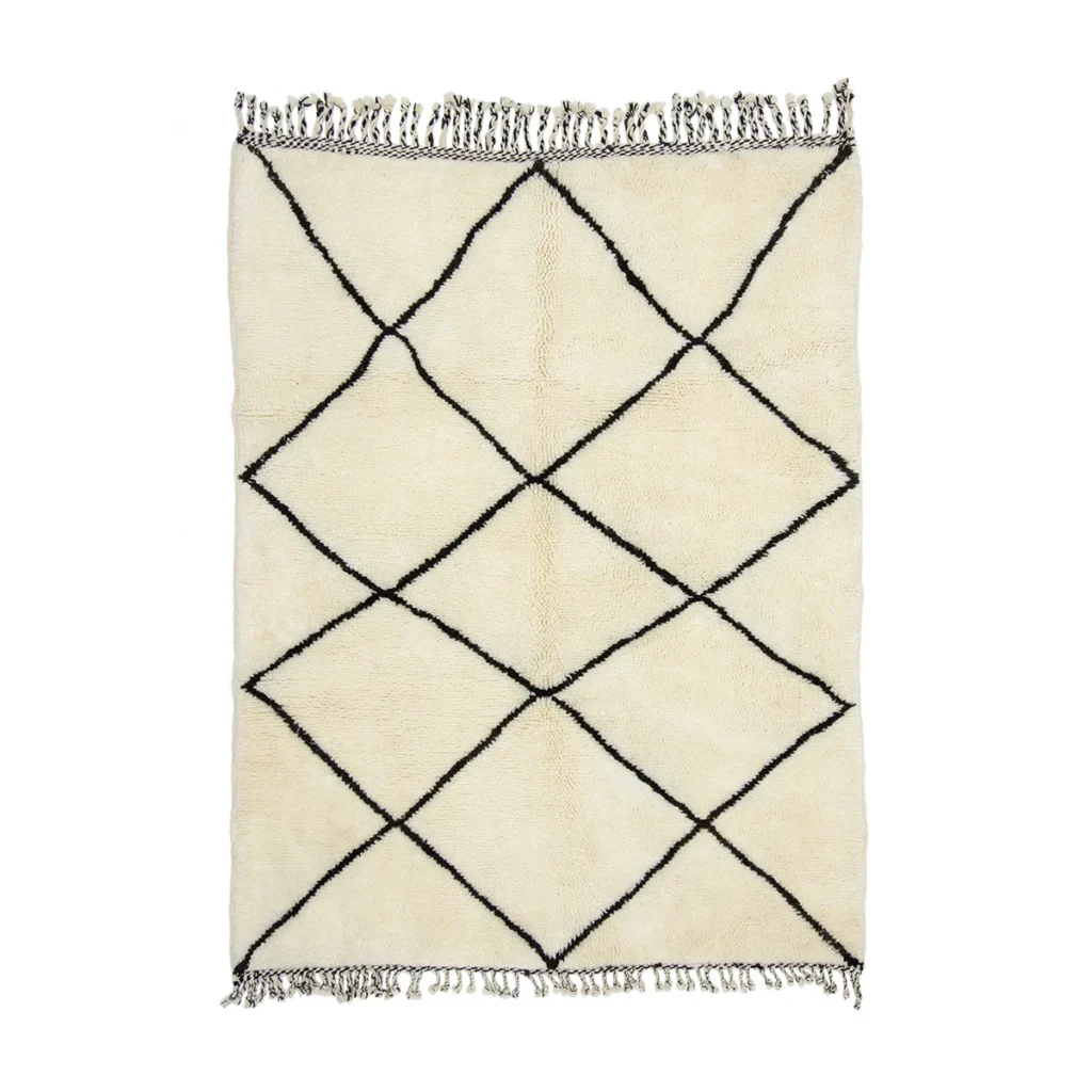 This luxurious cream-colored rug features a striking black diamond pattern and elegant fringed edges on the shorter sides, embodying the timeless craftsmanship of hand-knotted rugs.