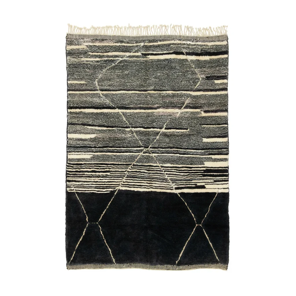 This authentic Moroccan rug, hand-knotted with skill, showcases a rectangular black-and-white design filled with abstract geometric patterns. Featuring horizontal lines and diamond shapes, the artisanal piece is completed with elegantly fringed edges.