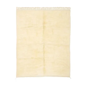 An artisanal, cream-colored rectangular rug features a slightly textured surface and elegant fringe along the top edge, reminiscent of authentic Moroccan rugs.