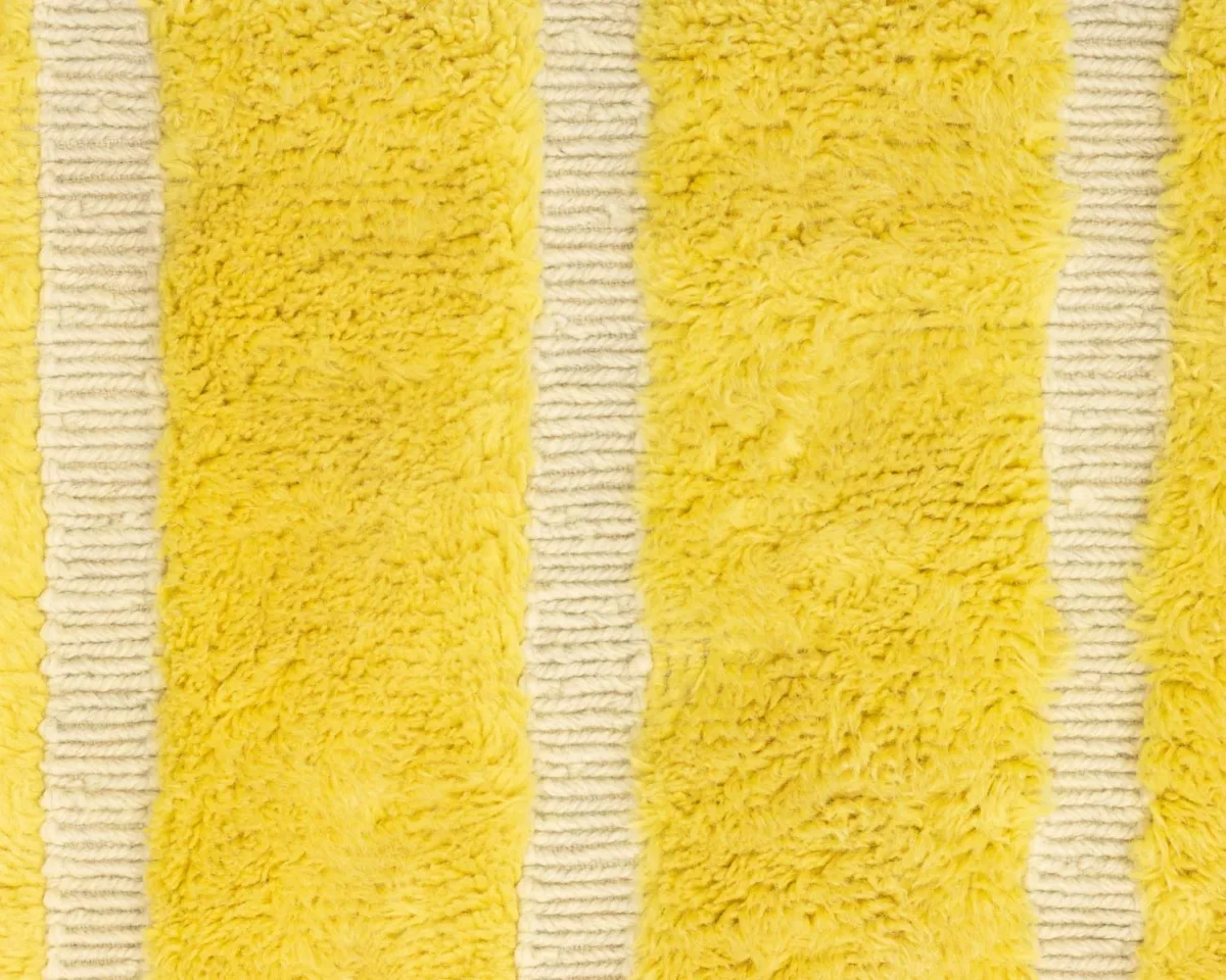 This luxurious fabric showcases a stunning design of alternating vertical fuzzy yellow stripes and smoother white stripes, reminiscent of exquisite luxury rugs.