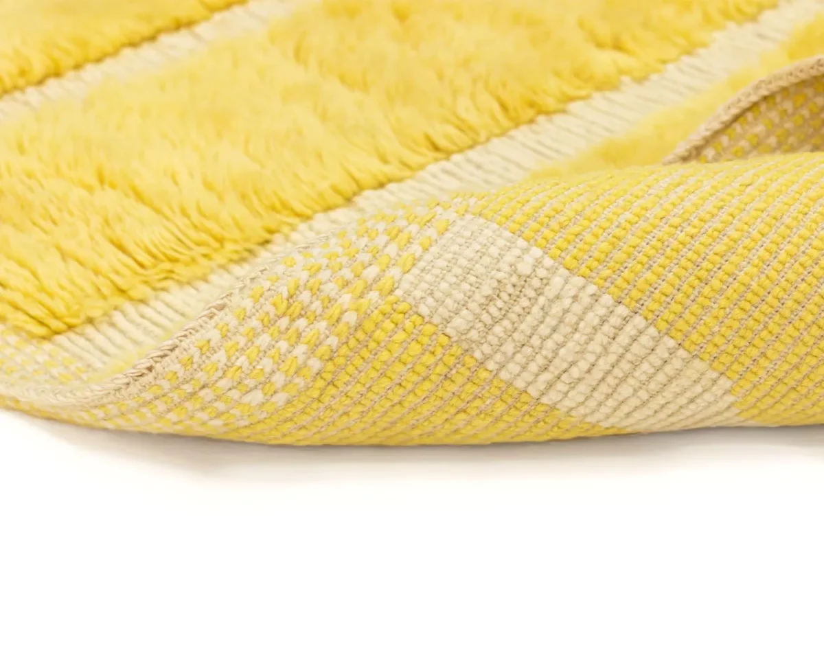 This close-up of a yellow and beige striped hand-knotted rug showcases its intricate woven texture and soft fabric underside, offering a touch of luxury to your home decor.