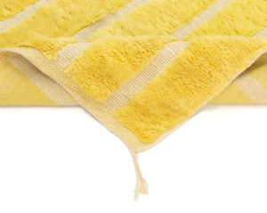 A folded yellow and beige striped item with a textured, fluffy surface and a loose thread at the corner is reminiscent of handmade home decor.
