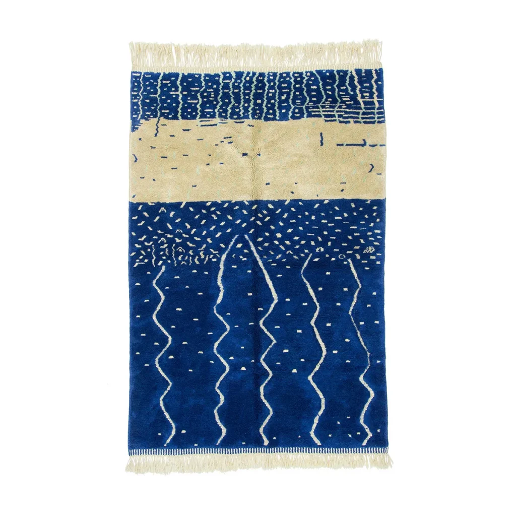This luxury hand-knotted rug showcases a blue and beige abstract pattern with wavy and dotted designs, complemented by elegant fringed edges.