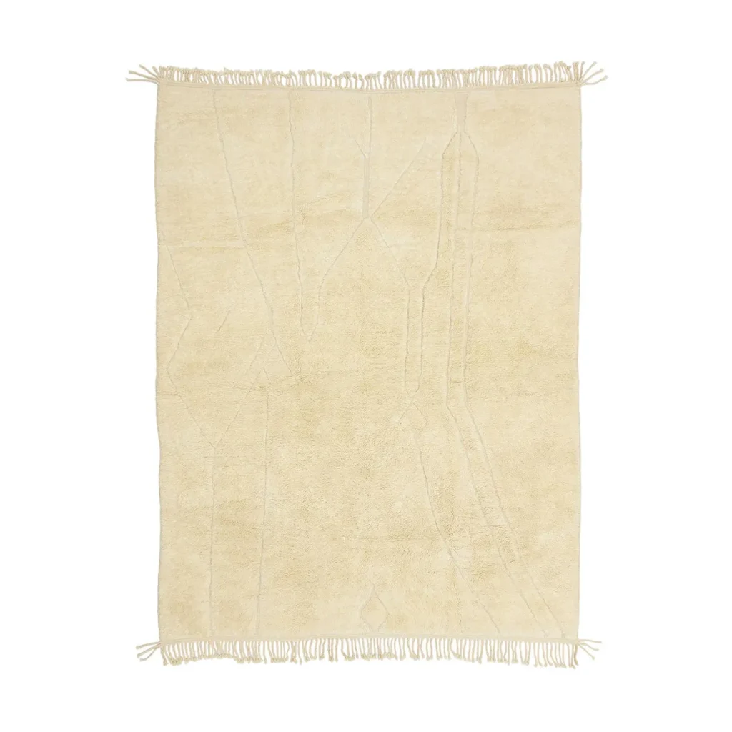 This artisanal rug features a subtle abstract pattern in beige, complemented by fringed edges on all sides. Hand-knotted with precision, it embodies timeless craftsmanship, making it an elegant addition to any space.