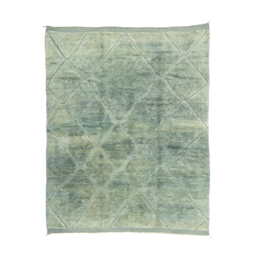 An artisanal, vintage-style rug with a subtle geometric pattern in shades of light green and grey. This hand-knotted design features intersecting diamond shapes, creating a textured and aged appearance that adds charm to any space.