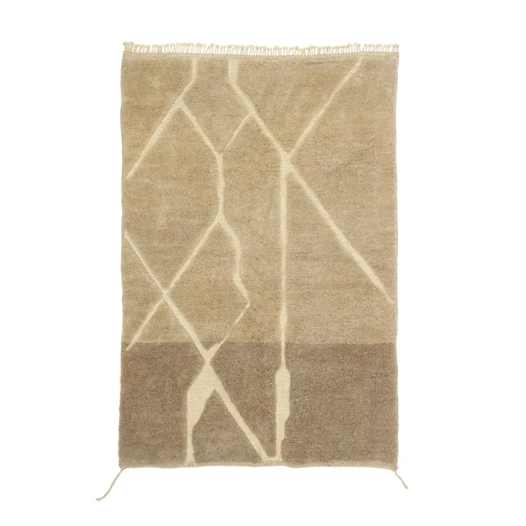 This artisanal rug is a rectangular beige piece with abstract intersecting line patterns in lighter shades. Its fringed edges on one side and hand-knotted details showcase exquisite craftsmanship, making it a perfect addition to any space.