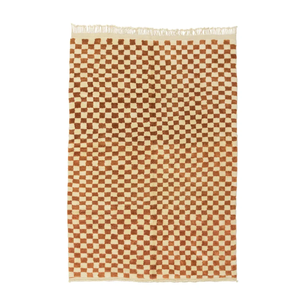 An artisanal, hand-knotted rug featuring a rectangular design with a brown and cream checkerboard pattern and fringed edges.