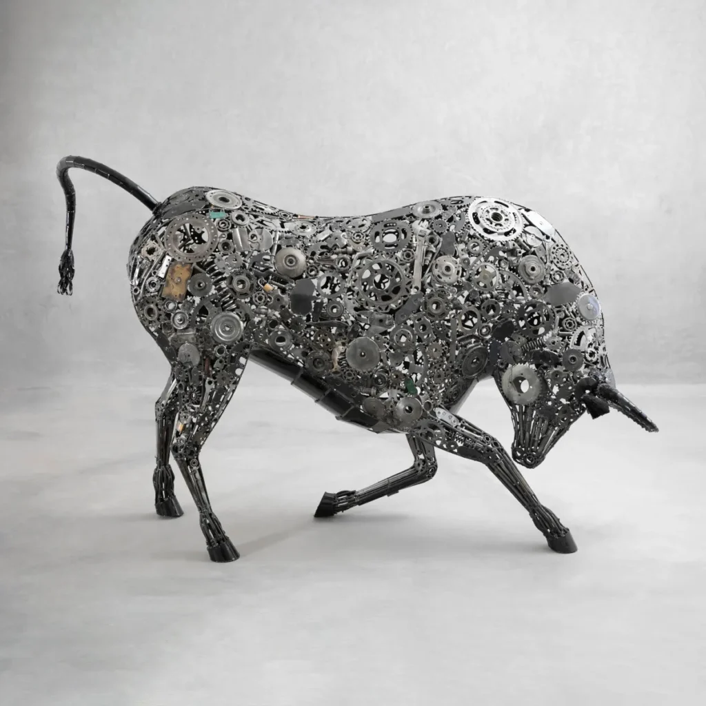 A bull sculpture made of various metal gears and parts stands on a light gray surface against a plain background.