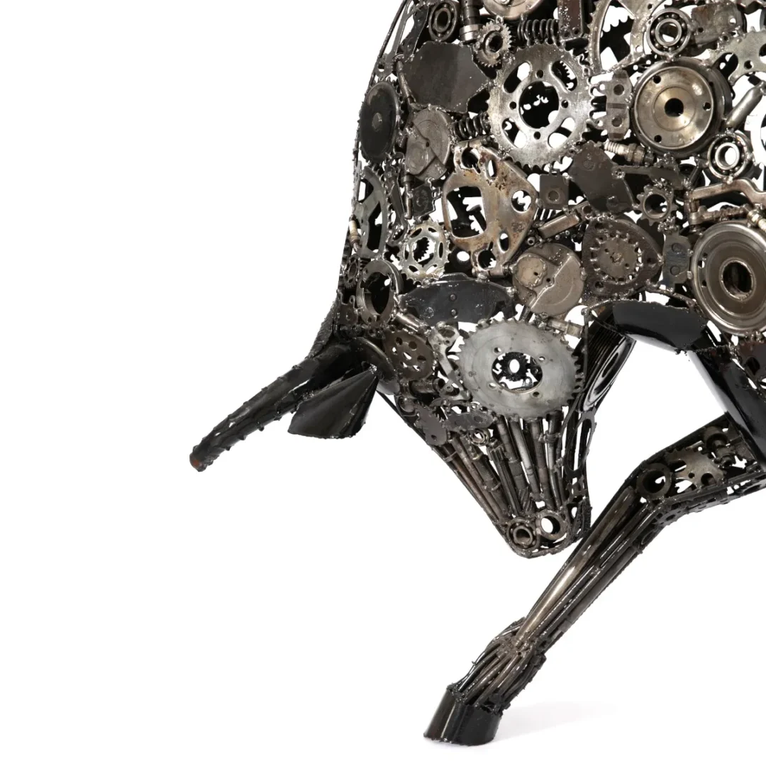 Sculpted from recycled metalwork, this striking wildlife creation features intricate gears and bolts, capturing the essence of a bull in motion against a plain white background.
