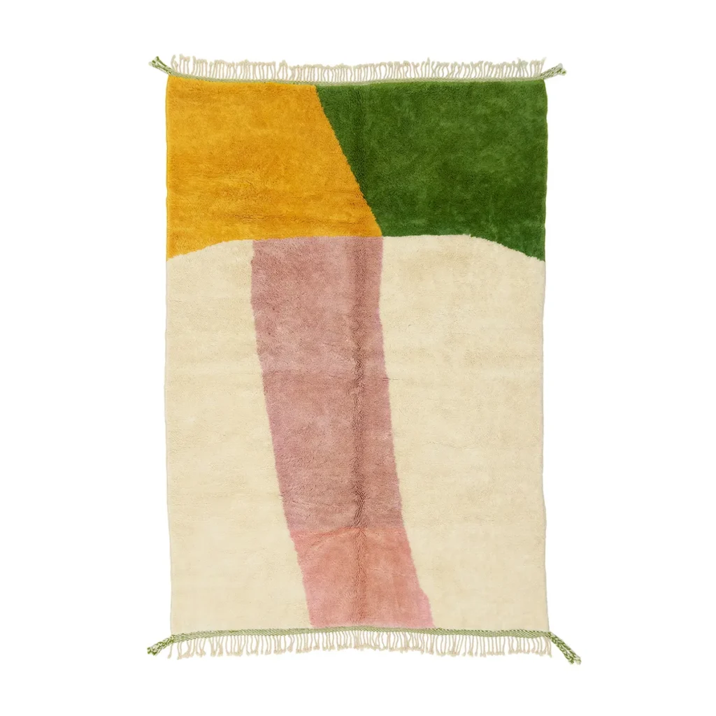 A rectangular area rug with abstract patches of yellow, green, cream, and pink. It features green fringe on the shorter edges.