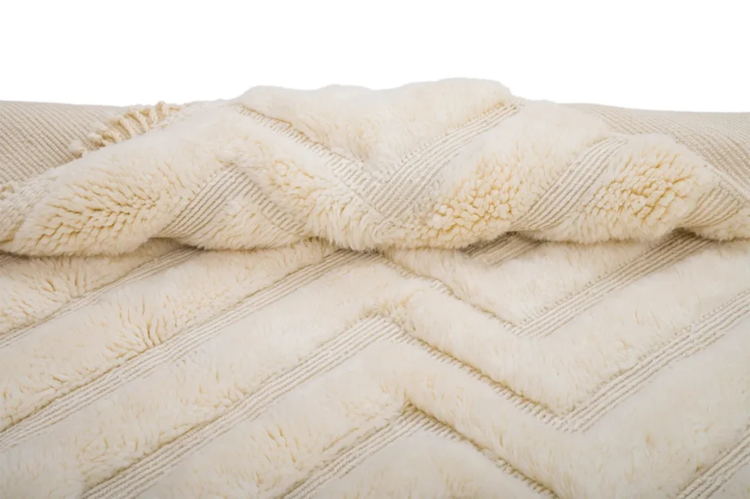 A close-up of a beige, fluffy blanket with a chevron pattern.