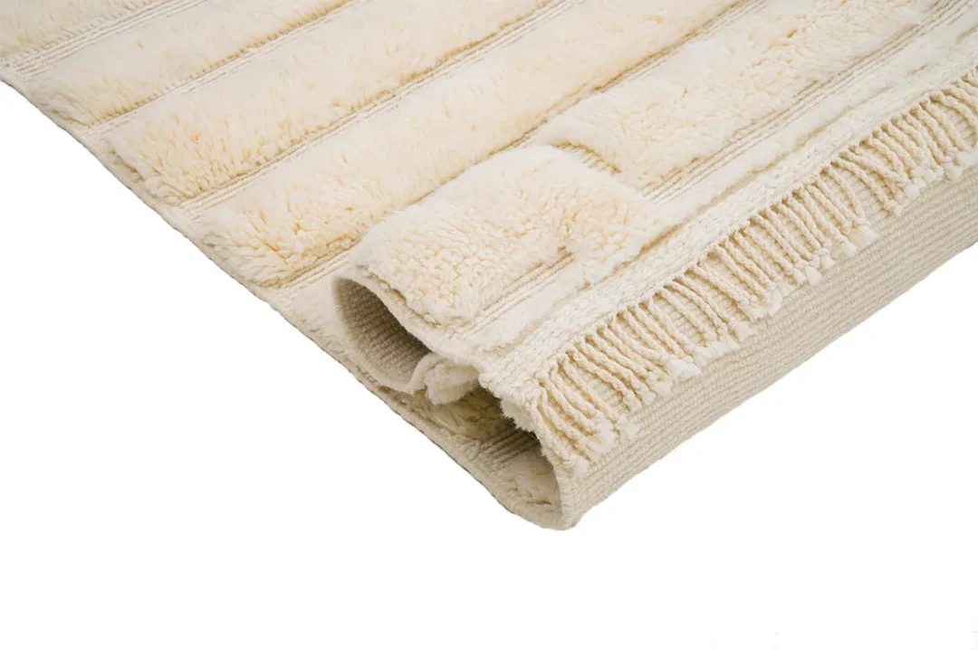 Close-up of a folded cream-colored textured towel on a white background, showing its woven and plush design.