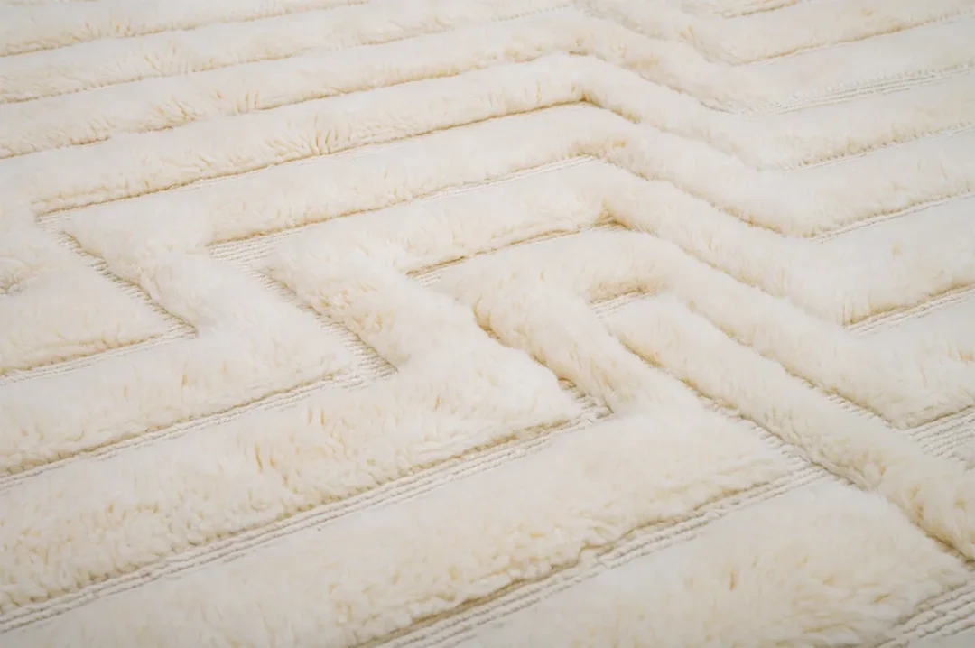 Close-up of a white, textured fur surface with a geometric, zigzag pattern, resembling a maze.