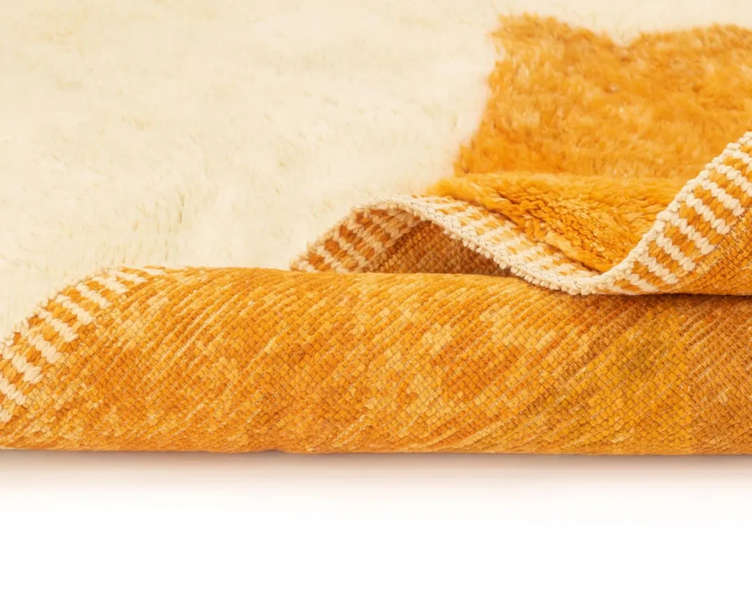 Close-up of a textured, two-toned orange and cream fabric with a woven pattern, showing layered and folded sections.