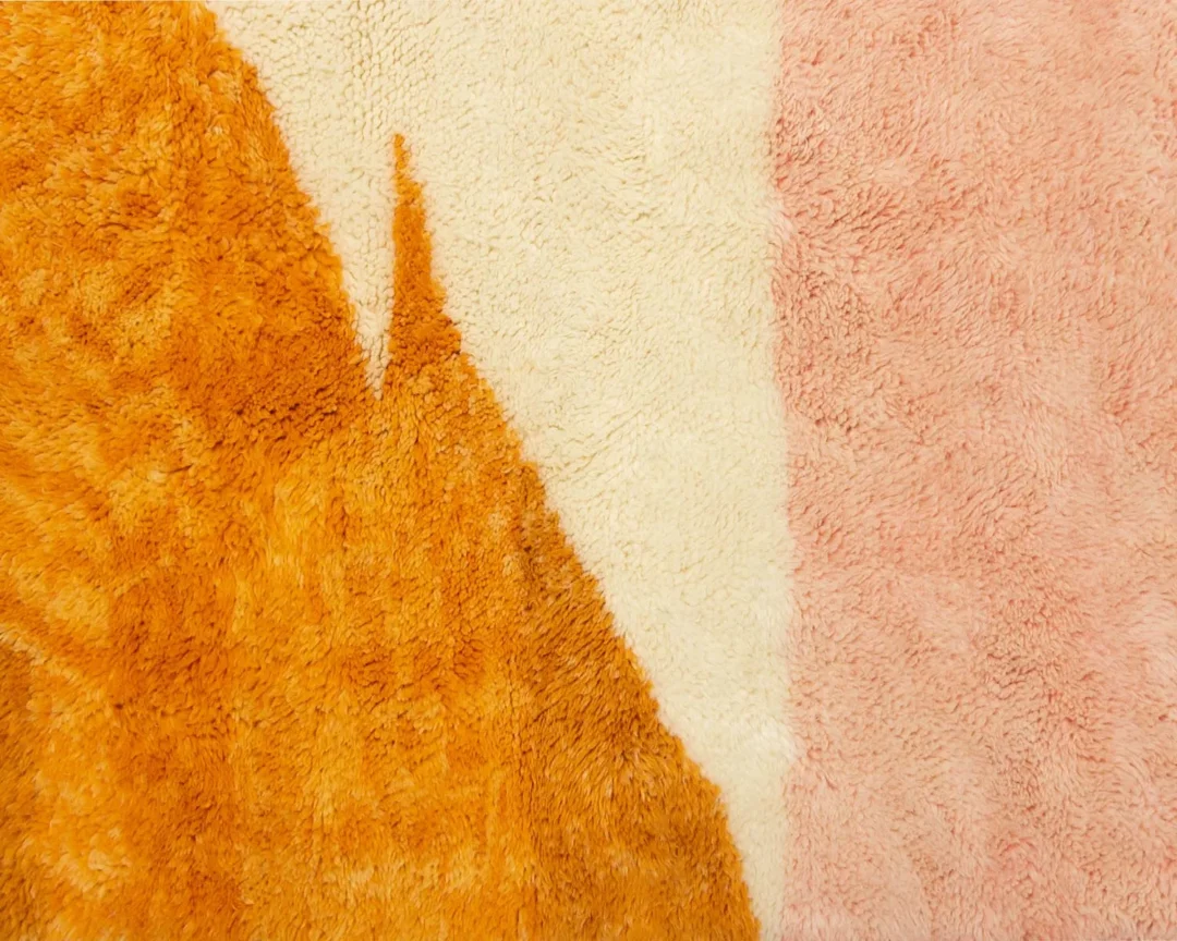 Close-up of textured fabric with an abstract design featuring orange, cream, and pink shapes.