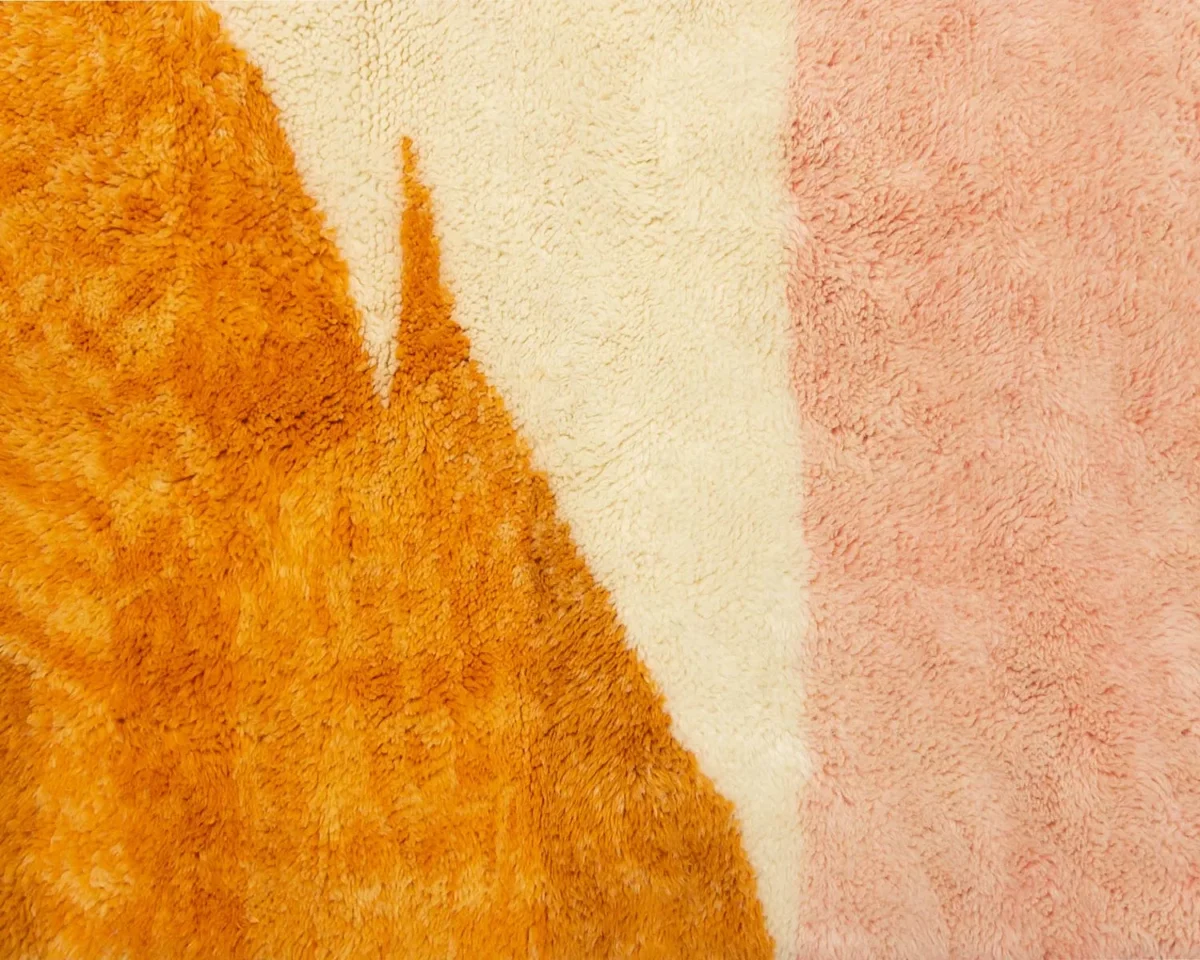 Close-up of textured fabric with an abstract design featuring orange, cream, and pink shapes.