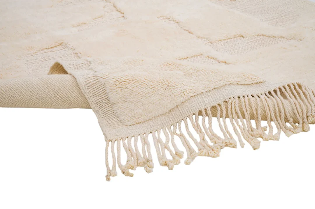 A beige textured rug partially rolled with fringed edges visible.