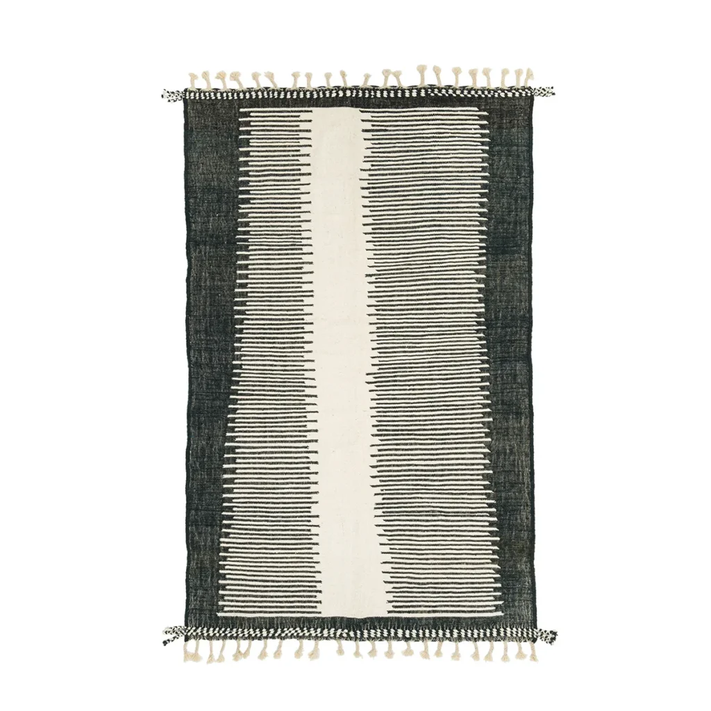 Rectangular rug with a central vertical stripe design in black and white. Features small black and white tassels on both ends.