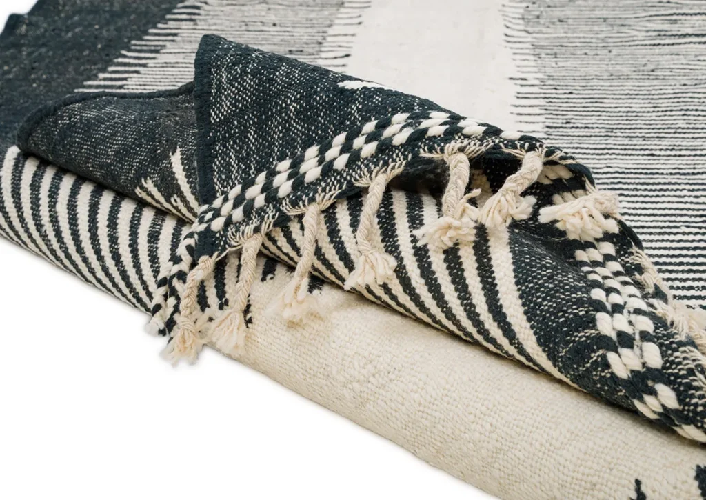Folded black and white woven fabric with dangling fringes on the edges.