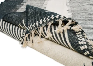 Folded black and white woven fabric with dangling fringes on the edges.