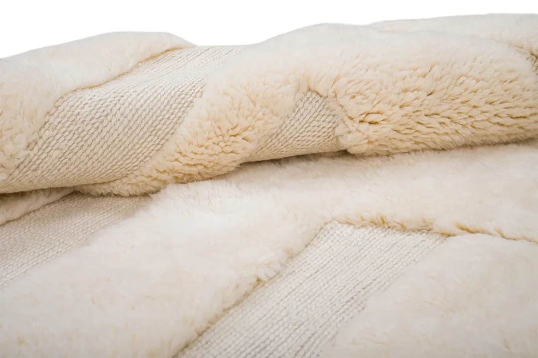 Close-up of a beige, textured fabric with alternating smooth and fluffy panels.