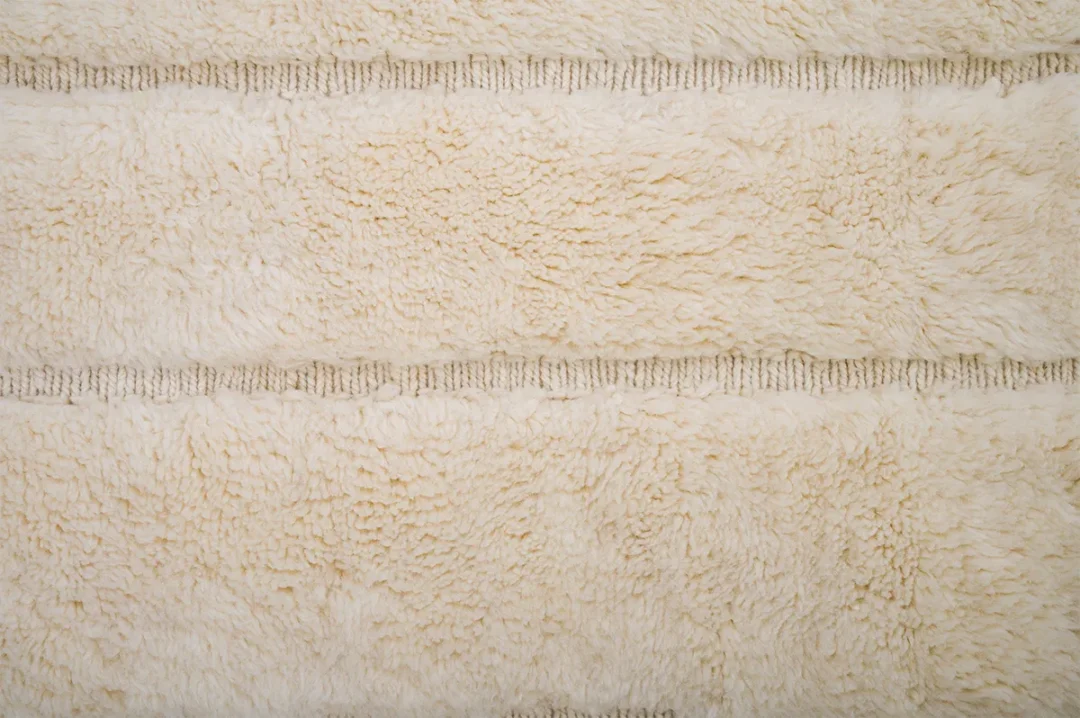 Close-up of a beige, textured fabric with a fluffy, soft appearance and two horizontal seam lines running across.