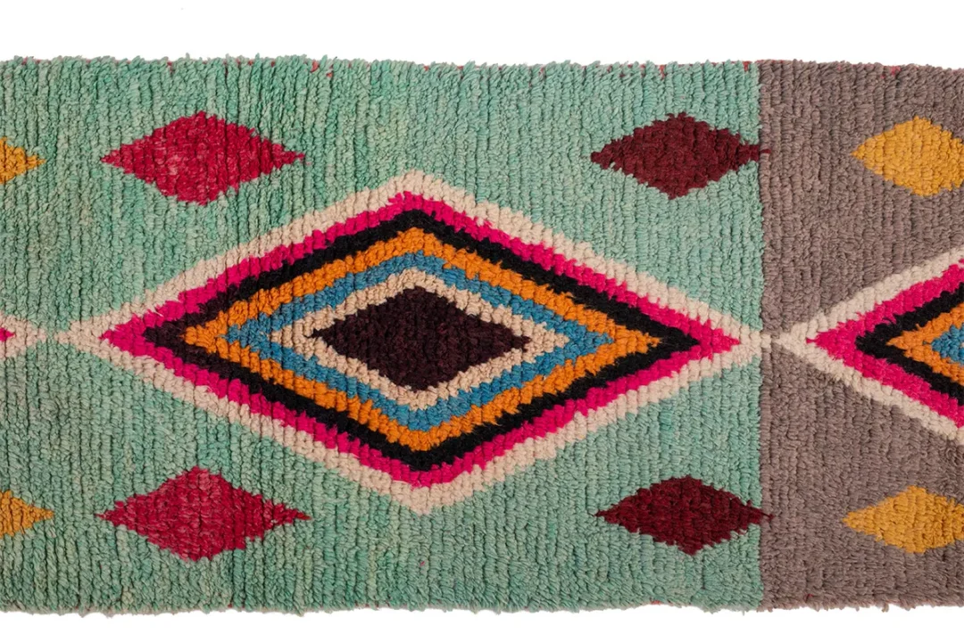 A colorful geometric-patterned textile with diamond shapes in turquoise, pink, yellow, red, black, and brown.