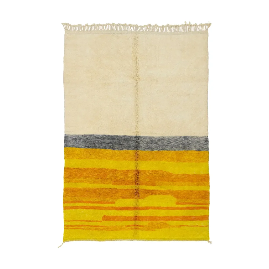 A rectangular rug with a beige top, a thin gray stripe, and a yellow bottom featuring horizontal orange patterns. Fringed tassels are on the top edge.